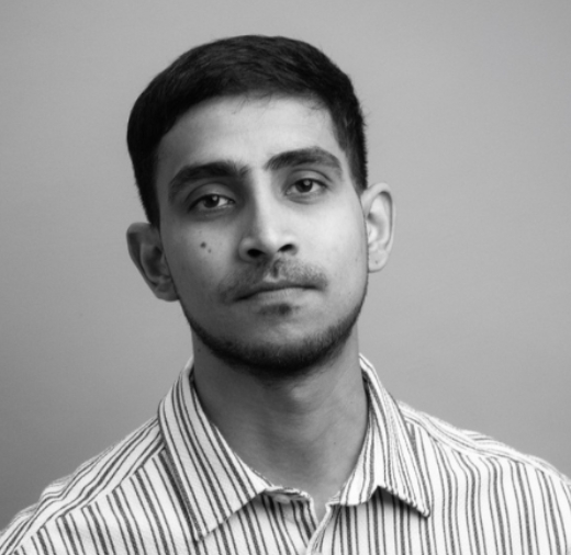 Portrait of a person with short hair and a striped shirt against a gray background.